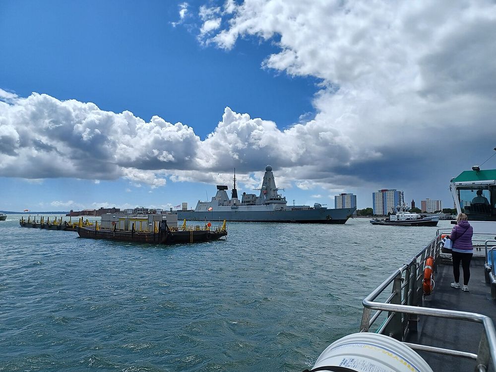 HMS Diamond (D34) returning to Portsmouth Harbour after active duty in the Middle East during which it intercepted Houthi drones, with ship's company on deck. Viewed from the Gosport Ferry en route from Portsmouth Harbour Station to Gosport. Hampshire, England.