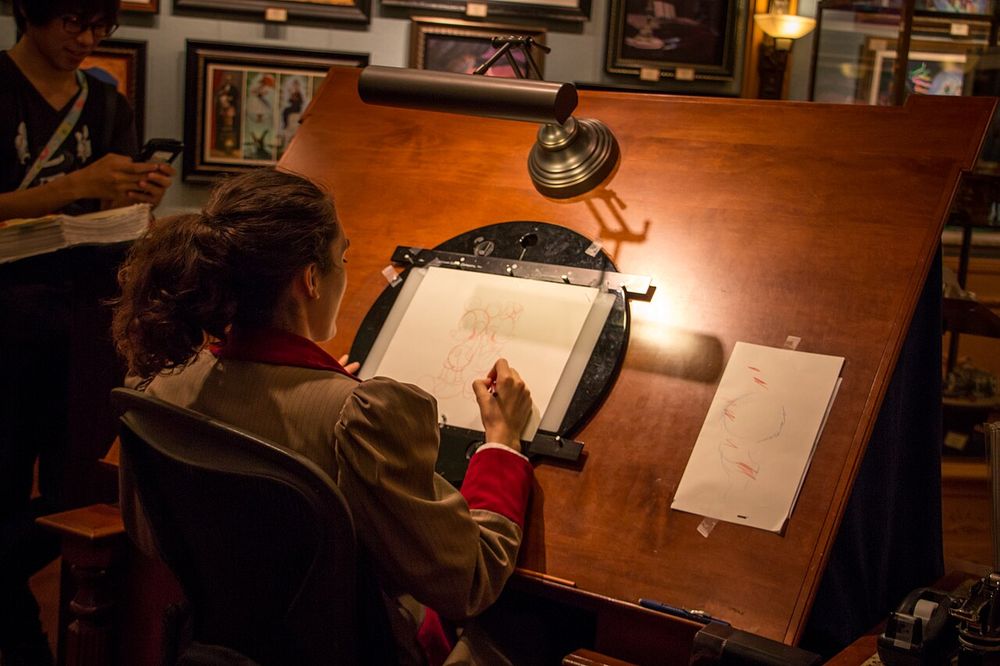 A Disneyland cast member sketching Mickey & Minnie inside the Disney Gallery on Main Street.
