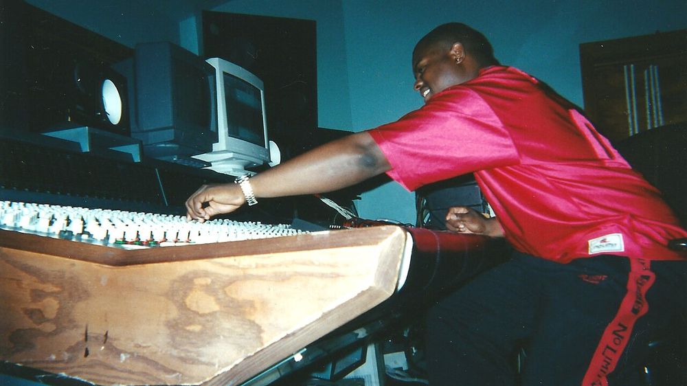 Music producer Donald XL Robertson working at a large-format mixing console during recording sessions for rapper Master P’s album Only God Can Judge Me. The photograph shows Robertson actively adjusting the mixing console inside a professional recording studio during the late 1990s No Limit Records 